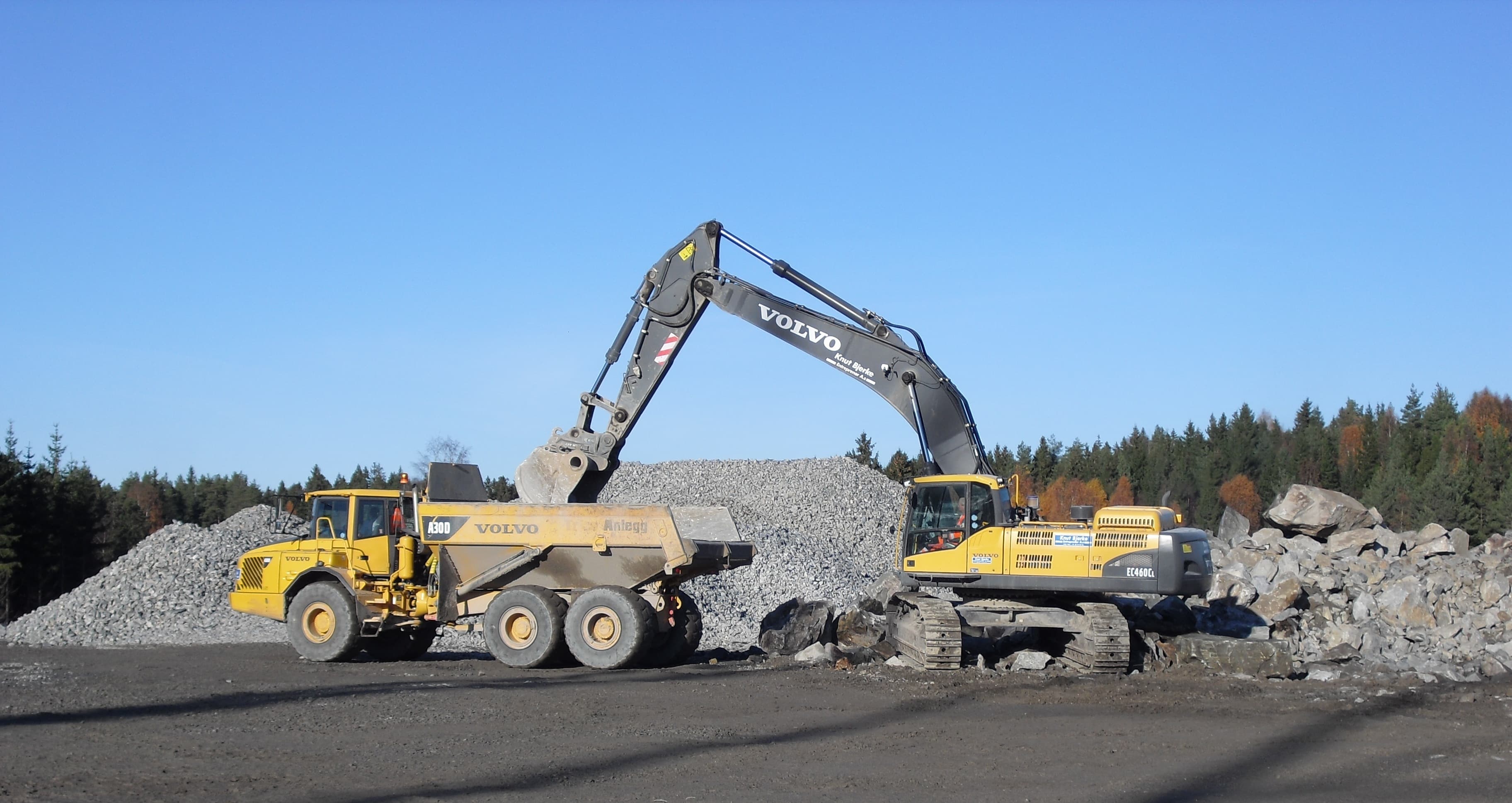 Gravemaskin og lastebil i arbeid på anleggsplass